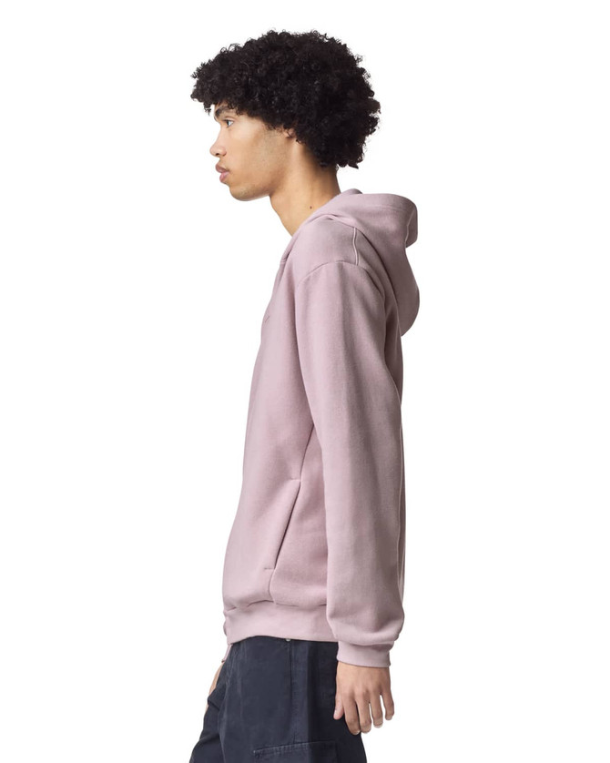 A unisex full zip hooded sweatshirt in light pink with a side view and a logo.