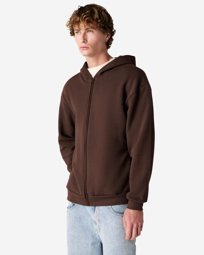 A unisex full zip hooded sweatshirt in brown, featuring a front zipper and a hood. The model stands with hands in pockets.