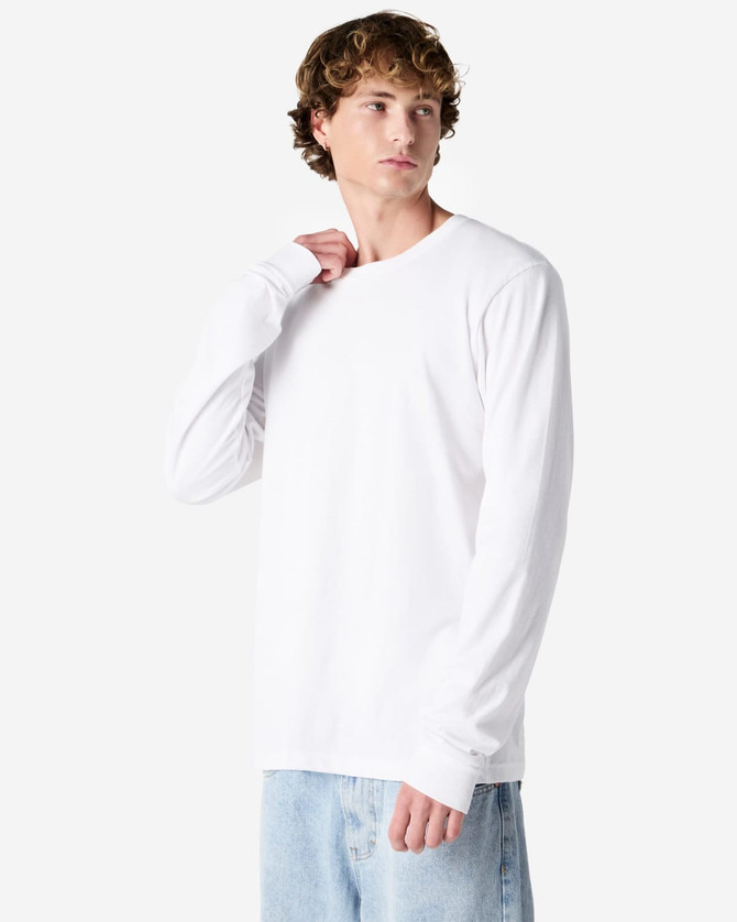 A long sleeve white t-shirt featuring a crew neckline, displayed by a model. The shirt has a logo.