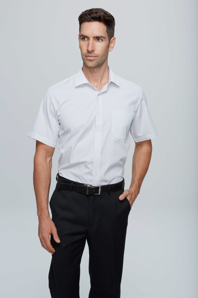 A short-sleeve button-up shirt in white, modelled by a man wearing black trousers. It features a pocket and a logo.