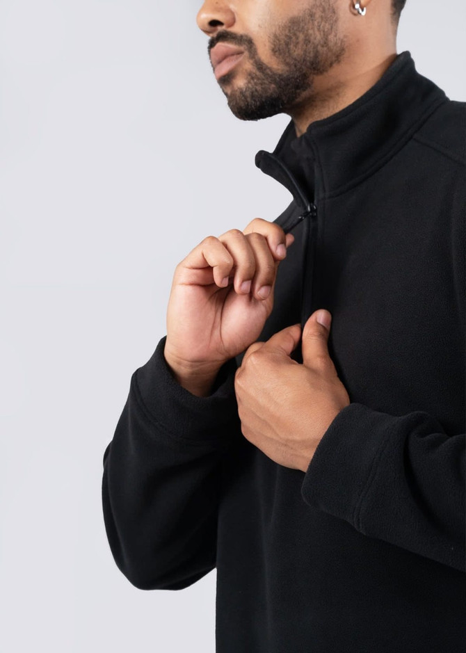 A man wearing a black polar fleece half zip top, with a close-up view of the zip and collar.