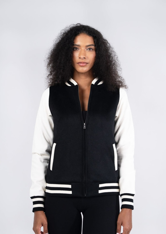 A black and white women's varsity jacket with a zip front, striped cuffs, and a logo on the chest.