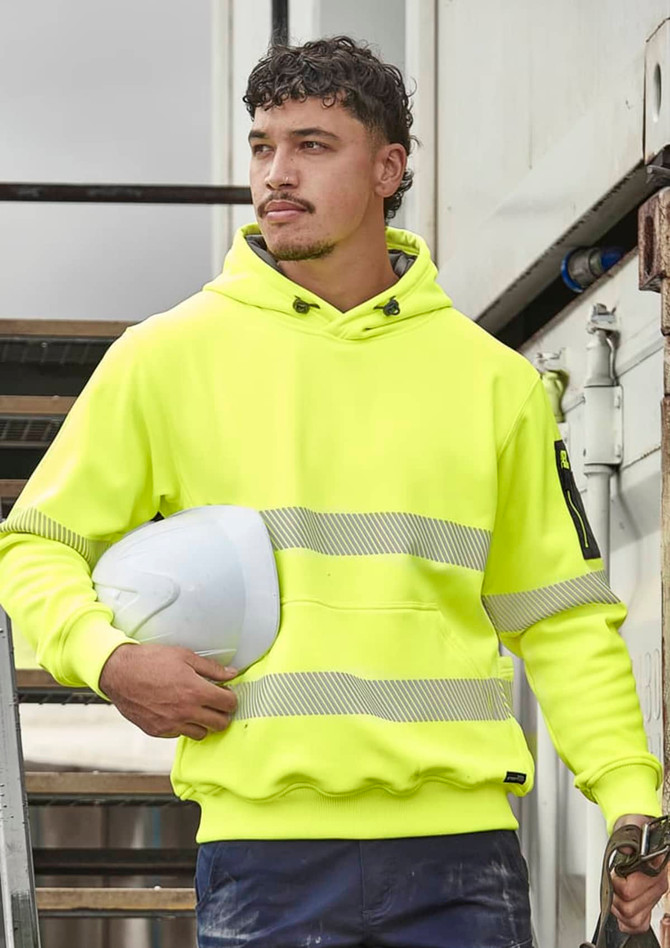 A bright yellow unisex hoodie with segmented tape and a hood, held with a white hard hat against a construction backdrop.