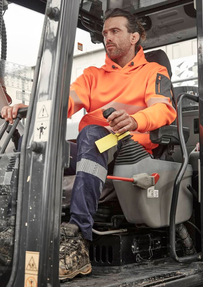 An orange water-resistant hoodie is worn by a man operating machinery, with segmented tape detail on the sleeves.