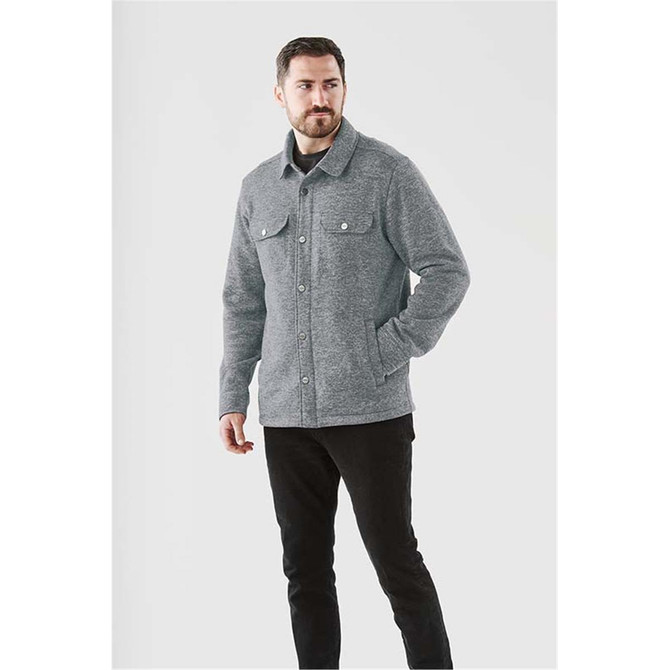 A grey unisex fleece shacket with a collared neckline and two chest pockets, worn by a model standing against a light background.
