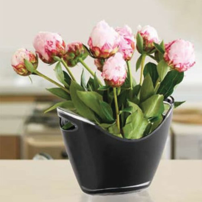 A sleek black ice bucket filled with pink peonies and green leaves, featuring curved sides and handles.