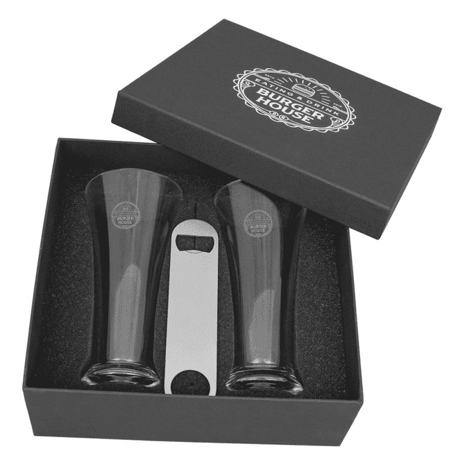 A set of two dark glass Pilsner beer glasses and a metal bottle opener in a black gift box.
