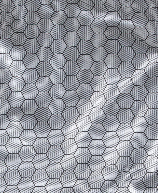 A close-up of a textured fabric featuring a hexagonal pattern in shades of grey and black, likely used in a puffer jacket.