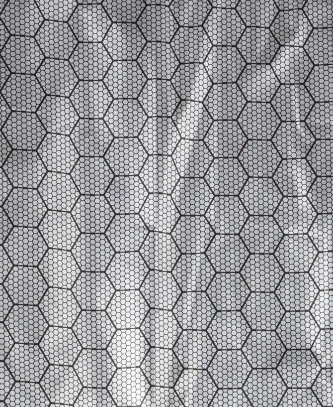 A close-up view of a hexagonal patterned fabric, featuring a black grid design over a light background.