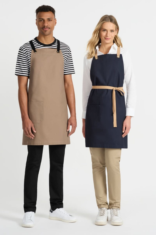 Two individuals wearing Brooklyn bib aprons; one in tan and the other in navy blue, with a logo displayed.