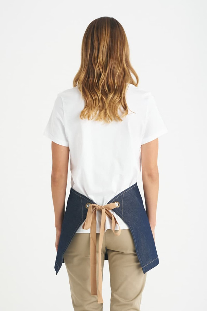 A short waist apron in denim with a tan tie, worn by a person facing away from the camera.