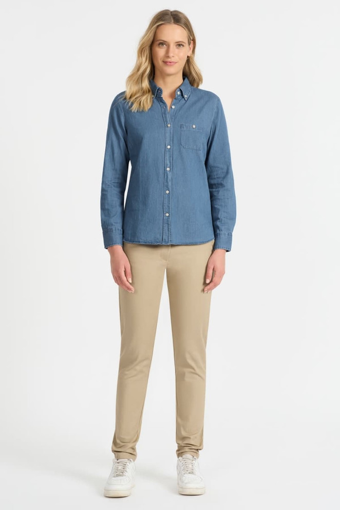 A long sleeve button-up shirt in denim blue, featuring a chest pocket and paired with light beige pants.