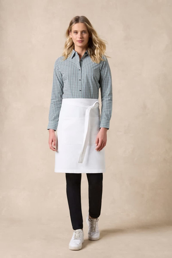 A woman is wearing a checkered long sleeve button-up shirt in green and white, paired with a white apron and black pants.