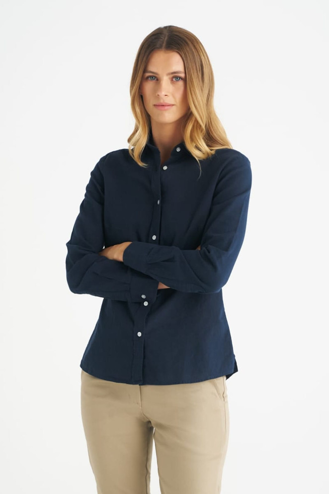 A long sleeve shirt in navy blue with a button-up front and a logo, styled for women.