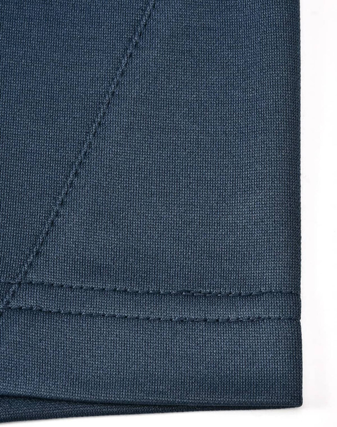 A close-up of a dark blue polo shirt fabric showing the seam detail and texture, featuring a logo.