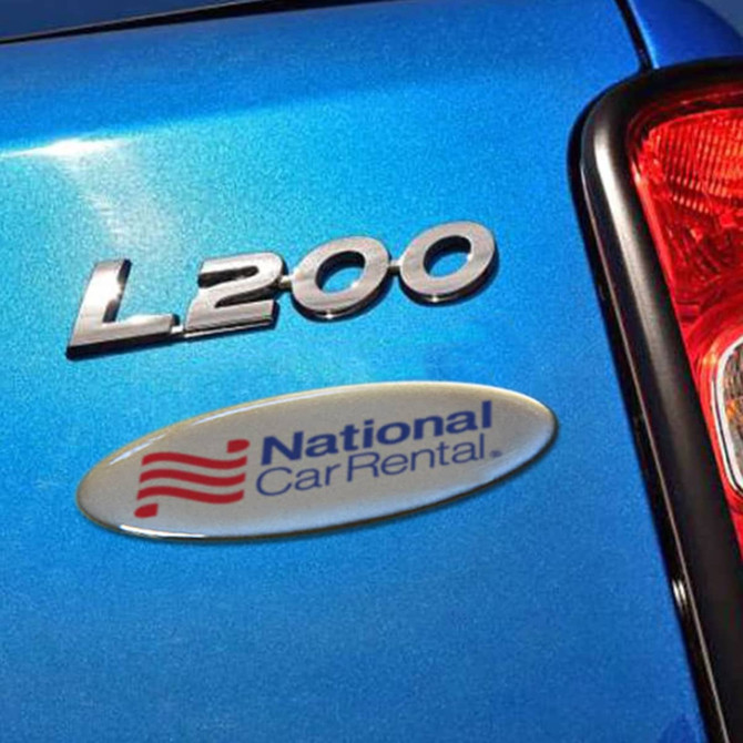 A blue car with a shiny oval label featuring a logo, placed beside the model name "L200."