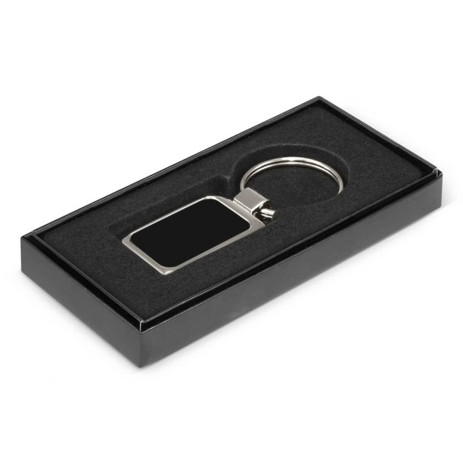 A metal key ring with a rectangular blank surface for laser etching, presented in a sleek black gift box.