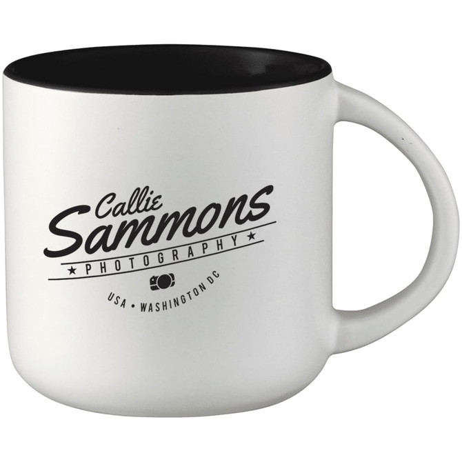 A ceramic mug with a white exterior and black interior, featuring a logo on the side.