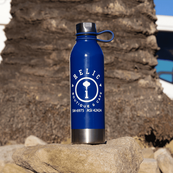 A drink bottle in blue stainless steel with a silver base and a logo on the front, set against a natural background.