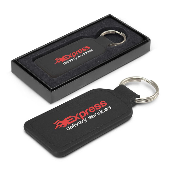 A rectangular black leather key ring with a metal ring, presented in a sleek box. It features branding.