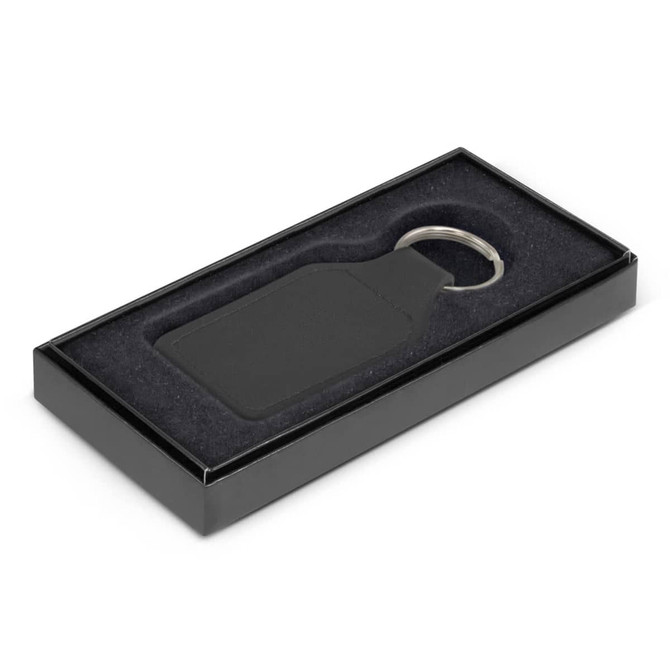 A black square leather key ring presented in an elegant black box with a soft interior.