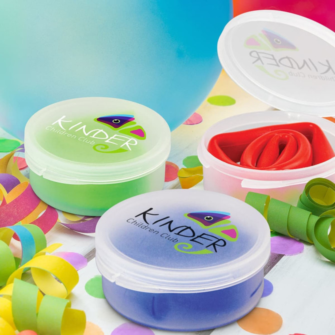 Two containers of colourful, flexible dough in green, red, and blue, with a logo on the lids, surrounded by confetti and balloons.