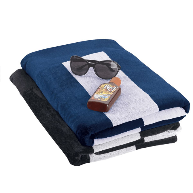 A stack of beach towels in navy blue, black, and grey, with sunglasses and a bottle of sunscreen on top.