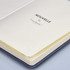 A navy notebook with cream pages, featuring a branding logo on the interior page.