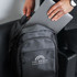 A grey laptop backpack being held while a silver laptop is being placed inside. The backpack has a logo.
