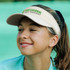 A beige sports mesh visor with a logo, worn by a young girl, set against a green background.