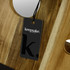 A wooden folding wine table with a natural finish, featuring a tag with a logo.