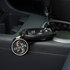 A round key ring in silver attached to a black car key, resting in a car's console.