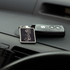 A rectangular key ring in black with a logo, sitting alongside a car key on a dashboard.