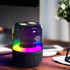 A Bluetooth speaker with a rainbow-lit base and a sleek, rounded design, featuring a logo and button controls.