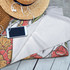 An Ocean XL Beach Towel featuring vibrant floral patterns in shades of orange and red, alongside a straw hat and headphones.