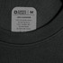 A close-up of a black t-shirt collar featuring a care label. The shirt is made of 100% polyester.