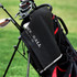 A black golf towel hangs from a golf bag, featuring a textured surface and a logo.