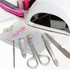 A vinyl manicure set with silver tools in a clear pouch, alongside a white nail lamp and pink nail files.