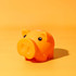 An orange piggy bank with black eyes on a yellow background. The piglet has a rounded shape and a glossy finish.