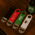 A drink bottle opener set featuring black, red, green, and white designs, each with a different logo.