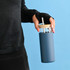 A drink bottle with a blue exterior, clear top, and bamboo lid, featuring a straw and held by a person.