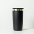 A drink bottle in matte black with a silver rim and a black lid. It features a branding logo.