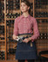 A denim half apron with a beige tie, worn by a model in a checked shirt, set against a wine rack background.