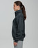 A grey 1/2 zip collar fleecy jumper displayed on a model from the side, featuring a smooth fabric and a logo.