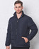 A navy heavy quilted puffer jacket with a zippered front and high collar, modelled by a man against a white wall.