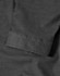 A close-up of a black pin dot stretch fabric with a 3/4 sleeve cuff of a button-up shirt. The shirt features a logo.