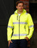A bright yellow softshell hooded jacket featuring reflective 3M tape, with zippered pockets and a branding logo.