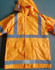 A high-visibility yellow safety jacket featuring reflective strips and a hood, with multiple pockets.