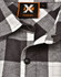 A black and white plaid unisex flannel button-up shirt featuring a collar and branded tag.