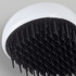 A hair detangler brush with a white handle and black bristles, featuring a round design.